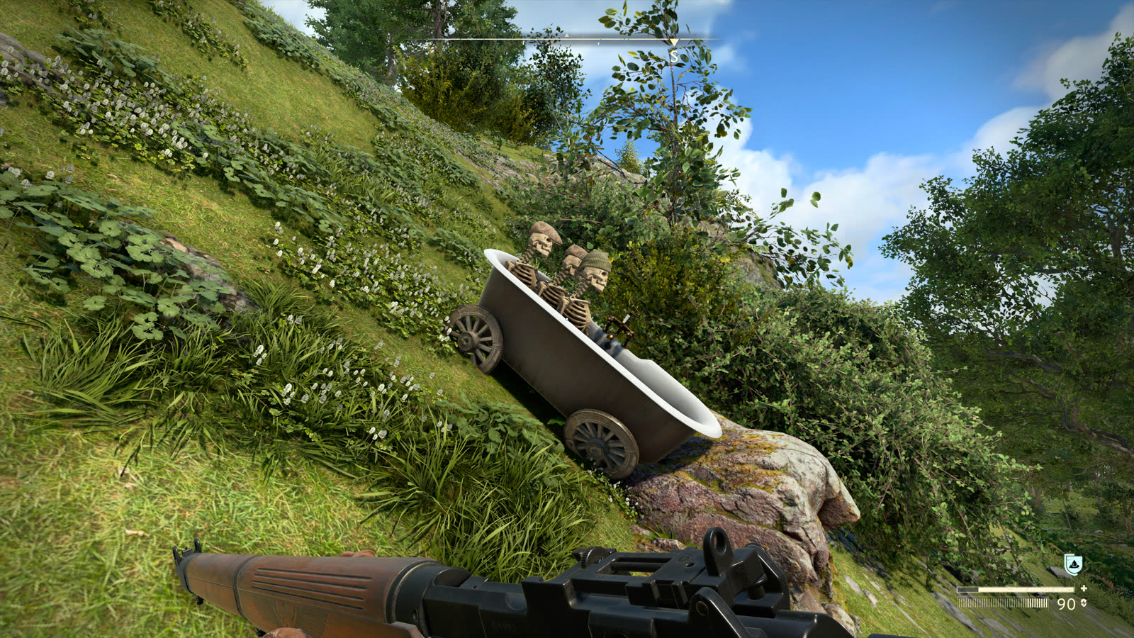 Three skeletons propped upright in a cast-iron bathtub mounted on cart wheels, parked on a steep grassy hillside under a clear sky. One wears a flat cap, another a knitted beanie.